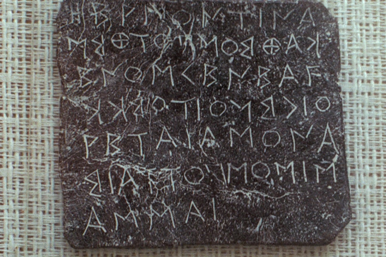 An ancient Greek oracular tablet from Dodona, featuring scratched inscriptions on a thin, dark lead sheet.