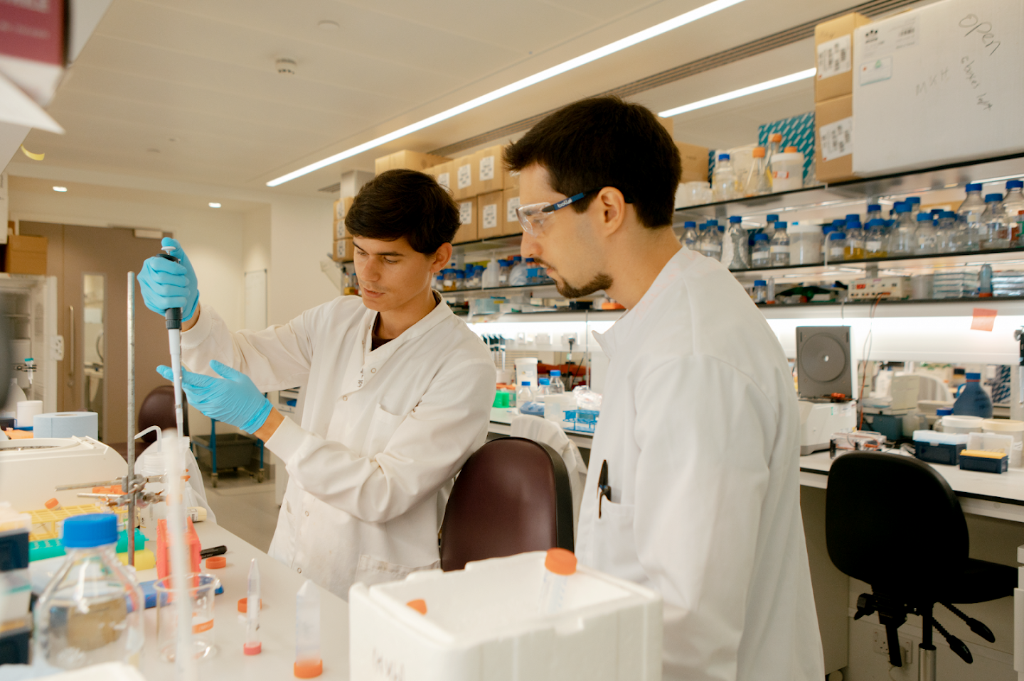 Two scientists wearing white coats, working in a laboratory.