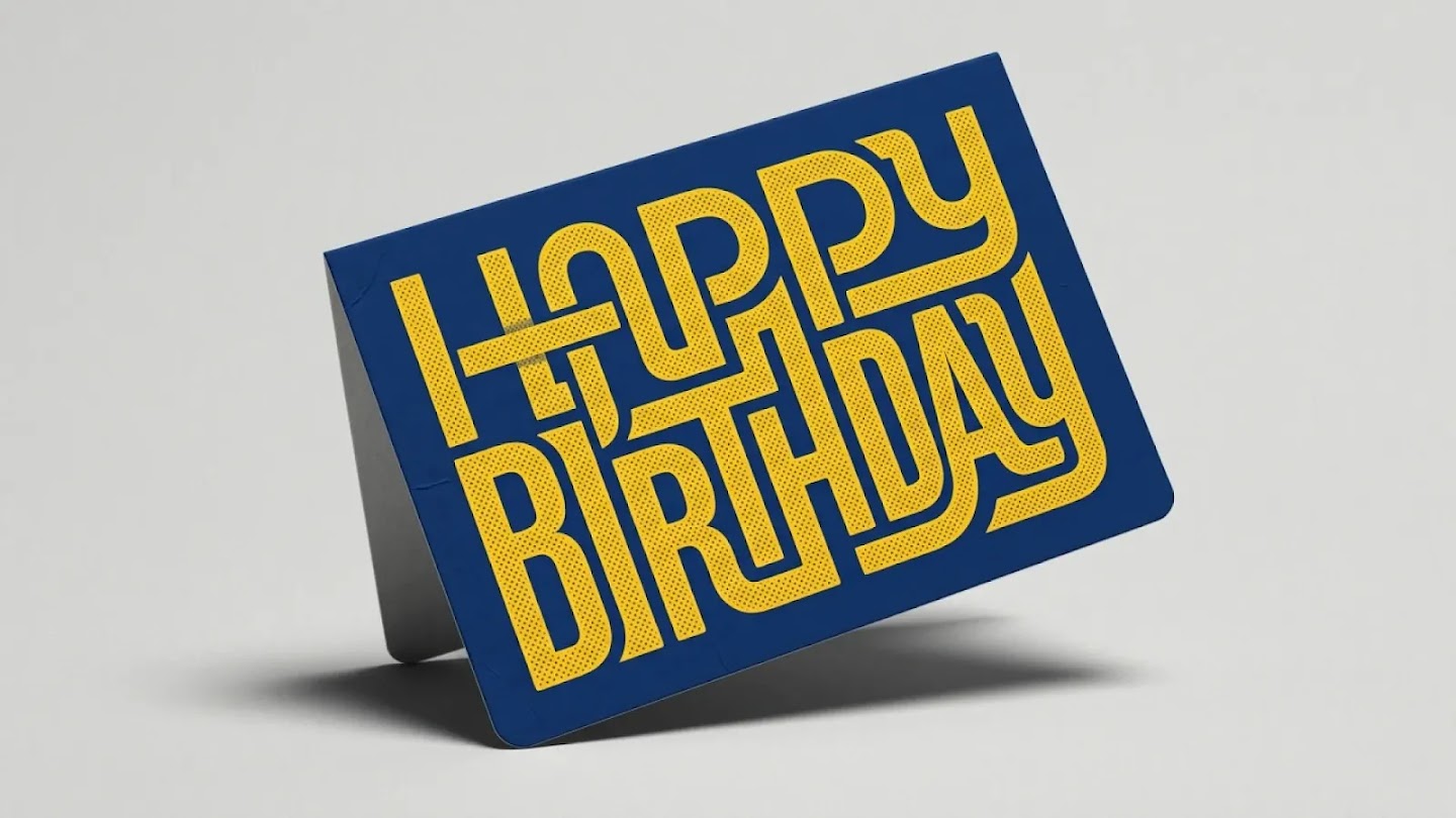 A dark blue greeting card stands at an angle, displaying "HAPPY BIRTHDAY" in thick, yellow, intertwined lettering. The font features a dotted pattern and a retro, labyrinthine design where the lines of the letters connect.