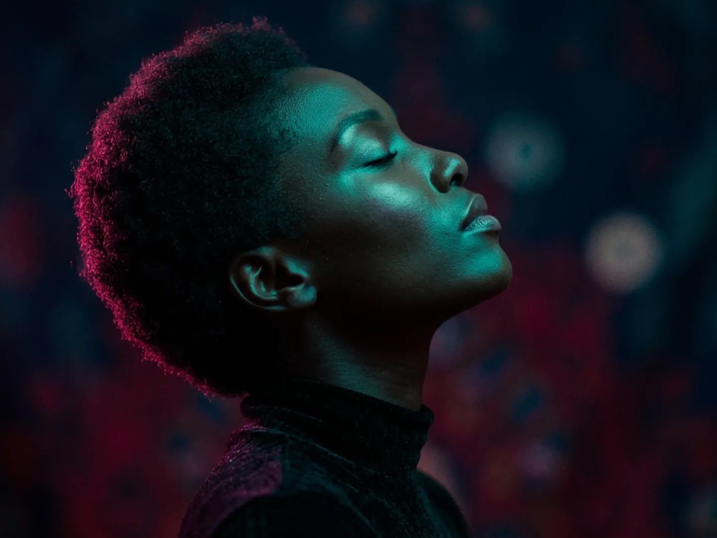 A profile portrait of a woman with short hair, illuminated by dramatic teal and magenta rim lighting against a dark, textured background. Her eyes are closed, and the high-contrast lighting emphasizes the contours of her face and the silhouette of her head.