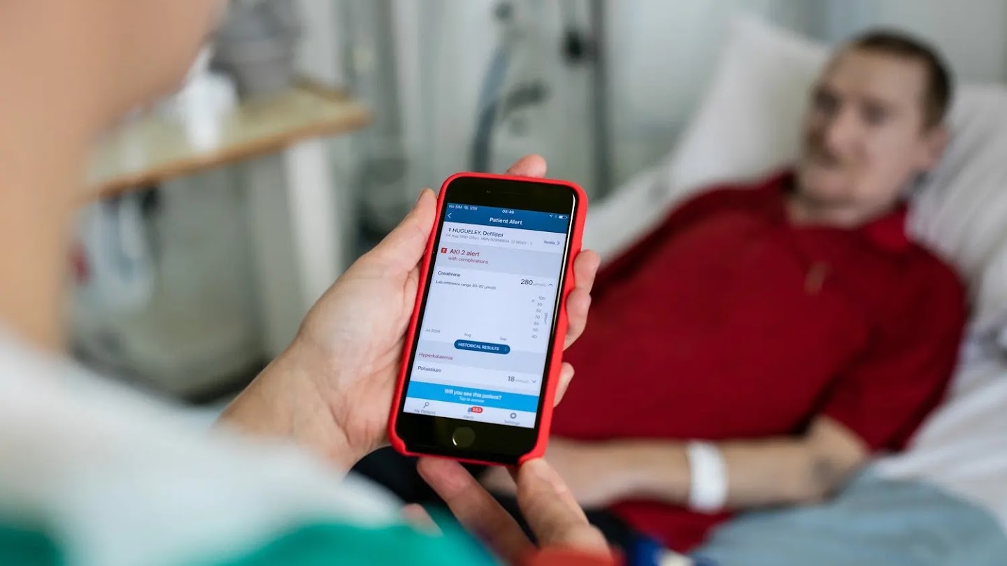 A medical professional using the Streams app by a patient's bedside.
